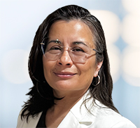 Woman with long dark hair and glasses, wearing a white blazer, posing against a blurred light blue background—exuding the professionalism often seen at Midwest Integrated Facility Services.